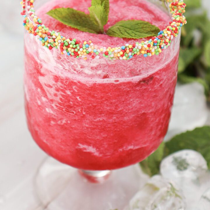 Watermelon slushie in a glass with sprinkles on the rim
