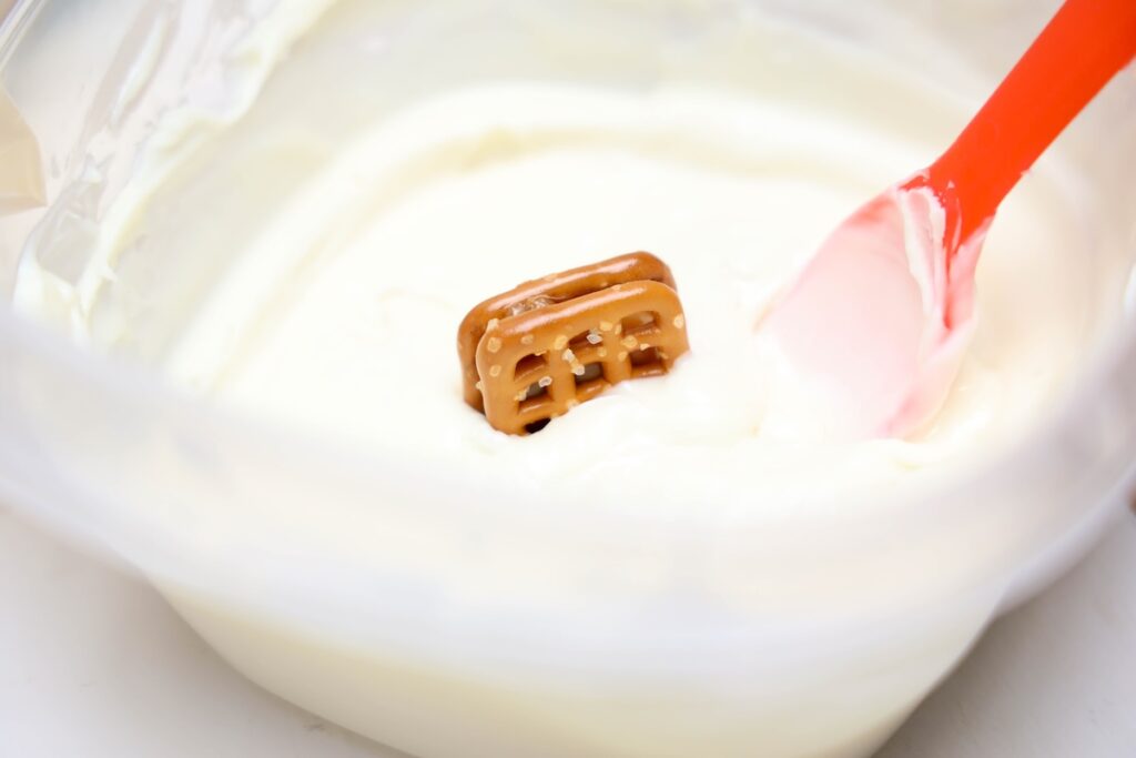 Caramel pretzel dipped into a bowl of melted white chocolate