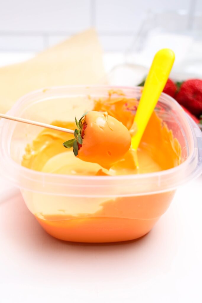 Dipping the strawberry into a bowl of melted candy