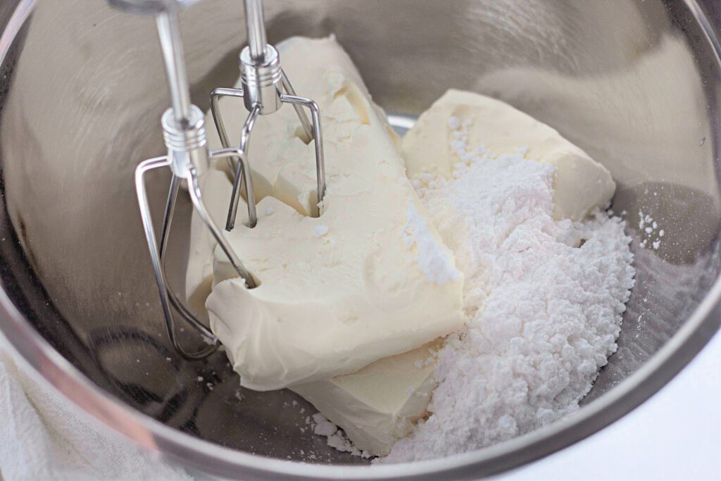Cream cheese and powdered sugar being mixed in a bowl