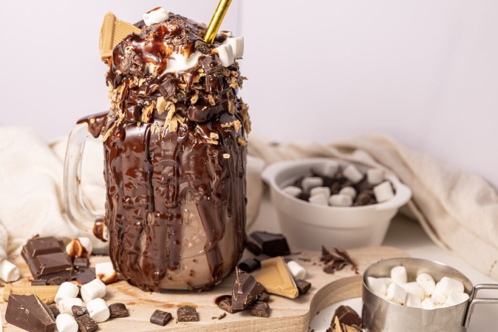 chocolate freakshake in a mason jar loaded with chocolate drink and topped with whipped cream and marshmallows
