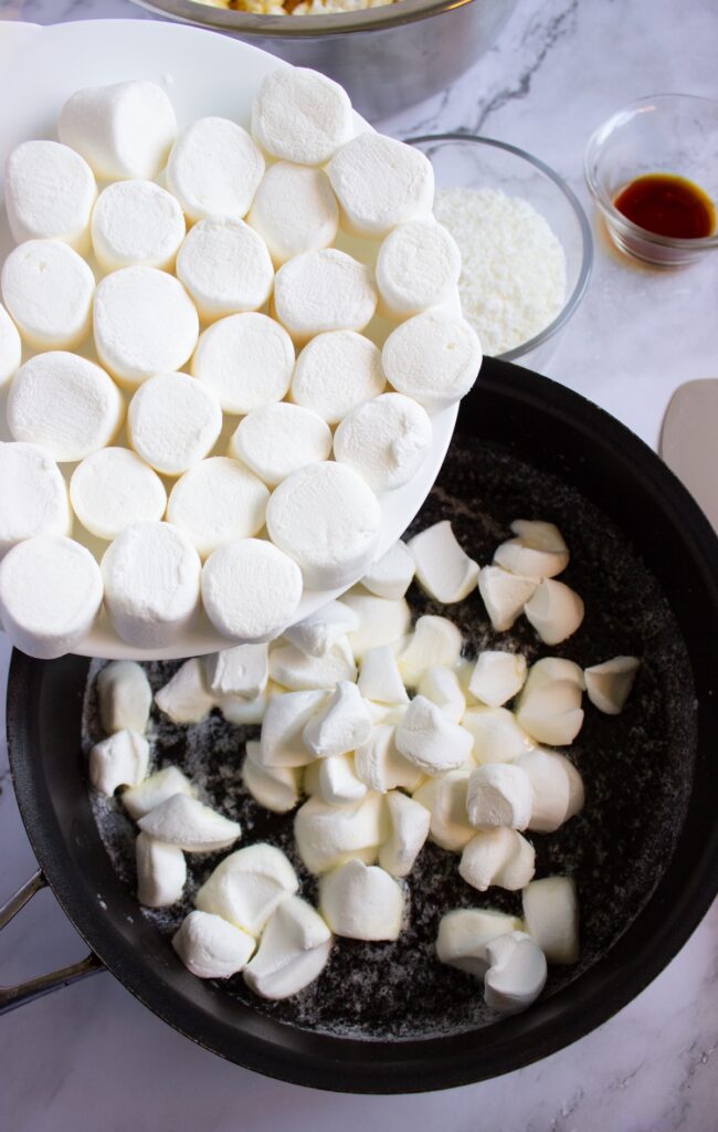 Marshmallows being added to a saucepan for coconut popcorn marshmallow snowballs recipe