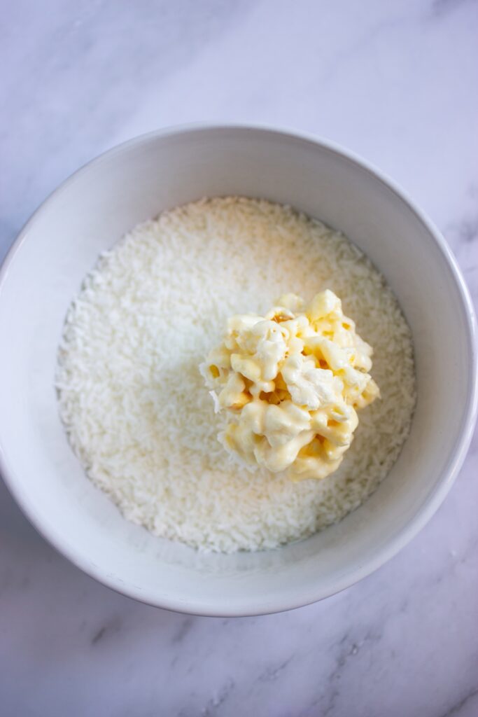 Coconut popcorn marshmallow inside a bowl full of coconut flakes