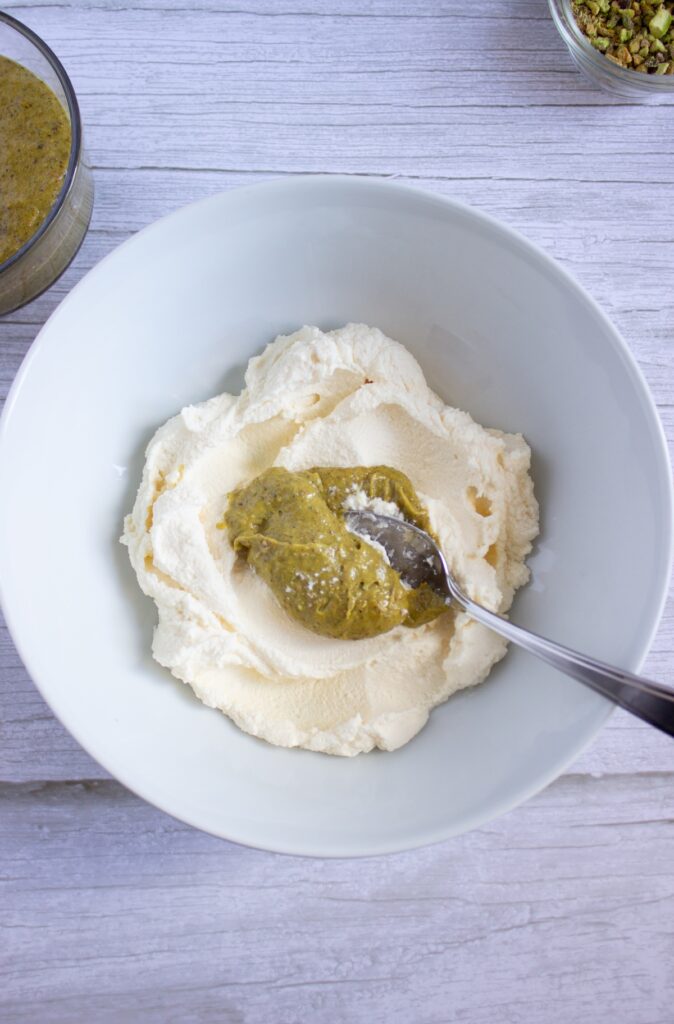 Mascarphone in a bowl with a tablespoon of pistachio cream