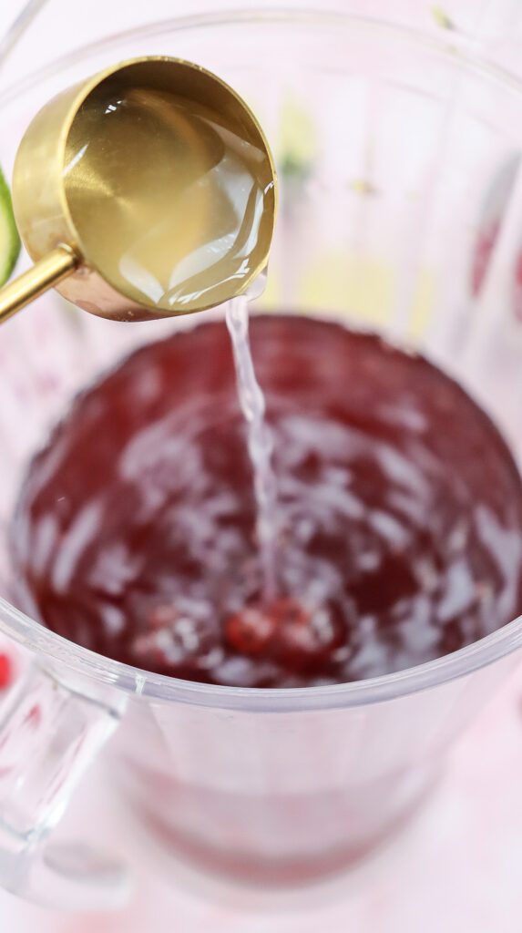 Pouring fresh lime juice into a big jug of pomegranate juice