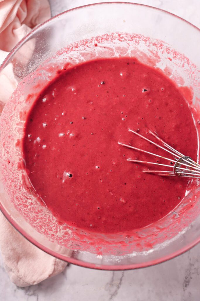 Wet ingredients for red velvet love bundt cake added with red coloring