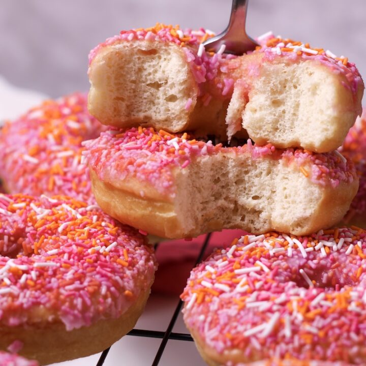 Stack of pink orange home made donuts with sprinkles