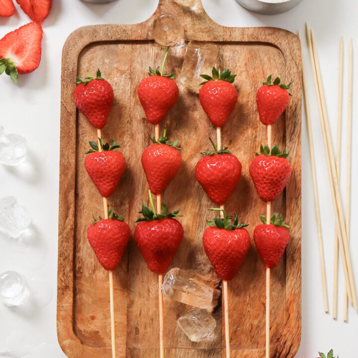 Strawberries on skewers laid down in a wooden chopping board