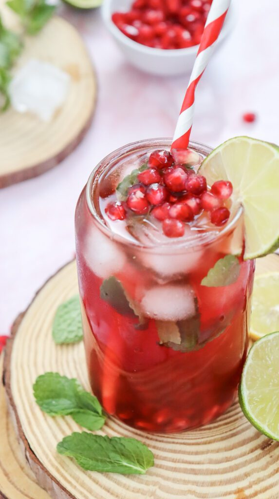 A glass of pomegranate fizz with ice and pomegranate seeds