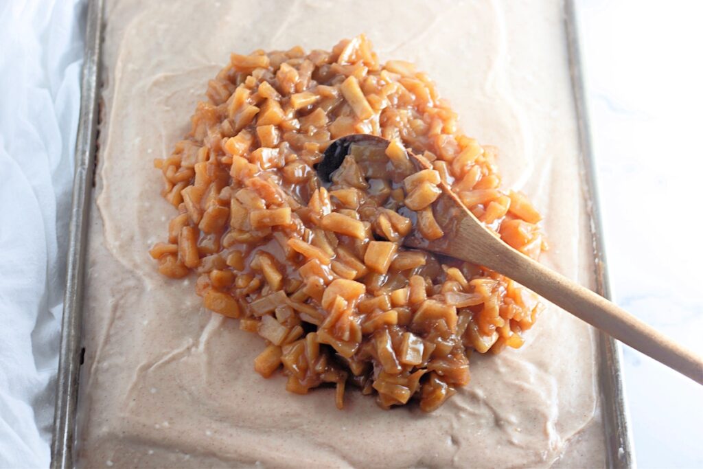 adding cooked apples to caramel apple sheet cake