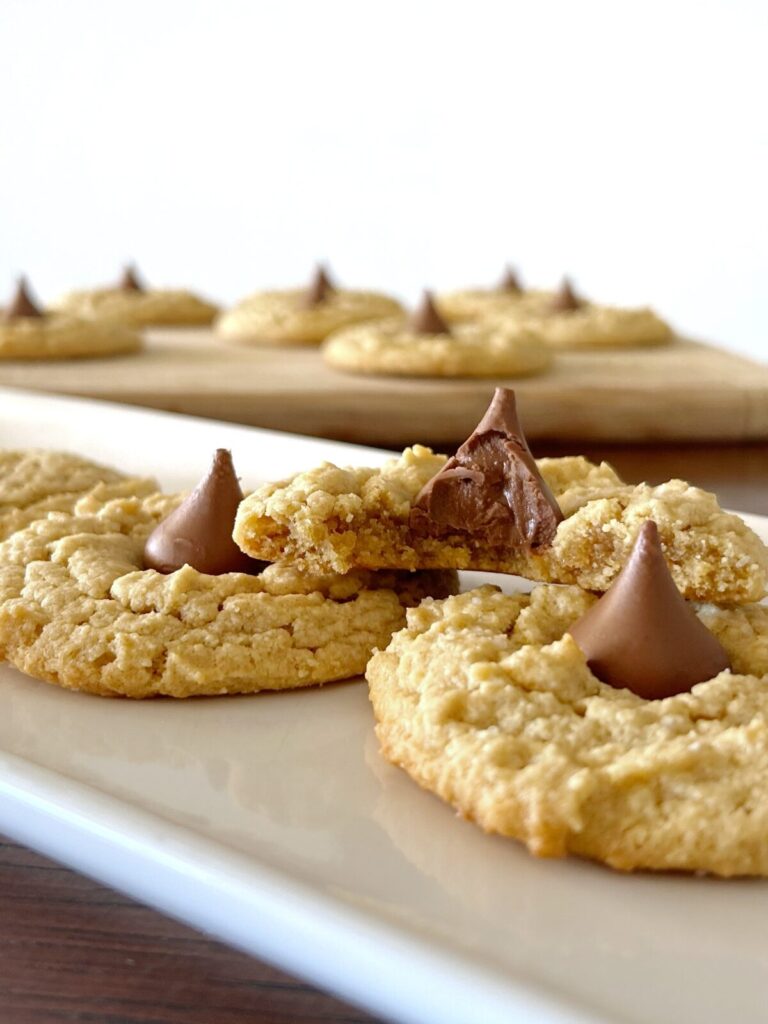 almond flour peanut butter blossom cookies topped with hershet kisses with one cookie bit in half