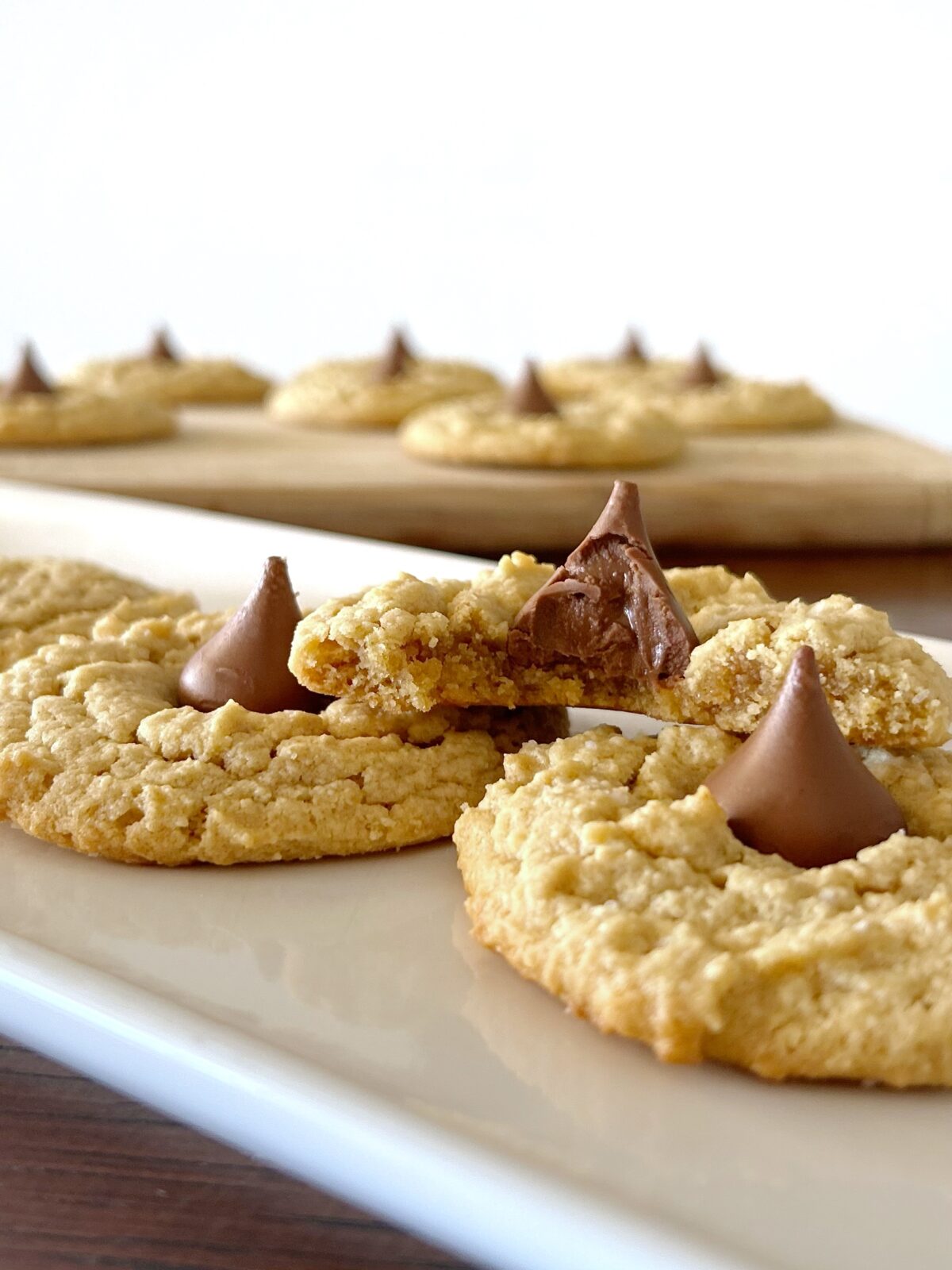 almond flour peanut butter blossom cookies topped with hershet kisses with one cookie bit in half