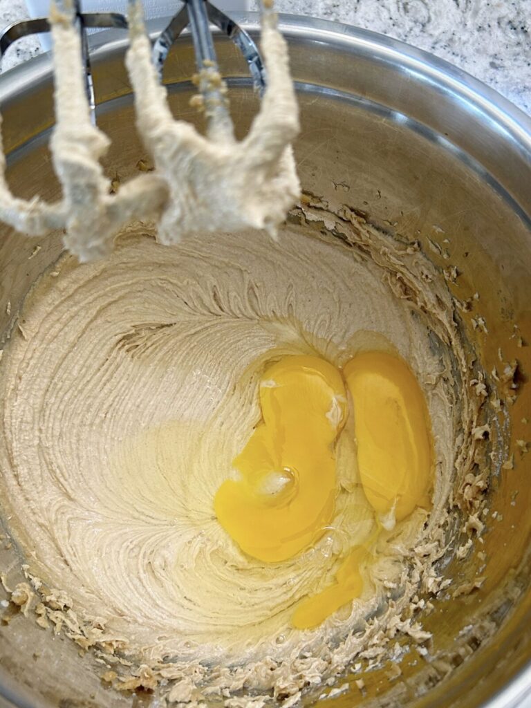 adding eggs to the sugar, butter, and peanut butter mixture