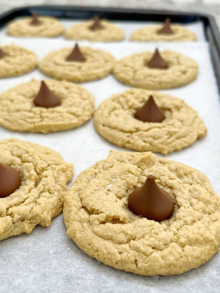 pressing hershey kisses on top of each baked cookie