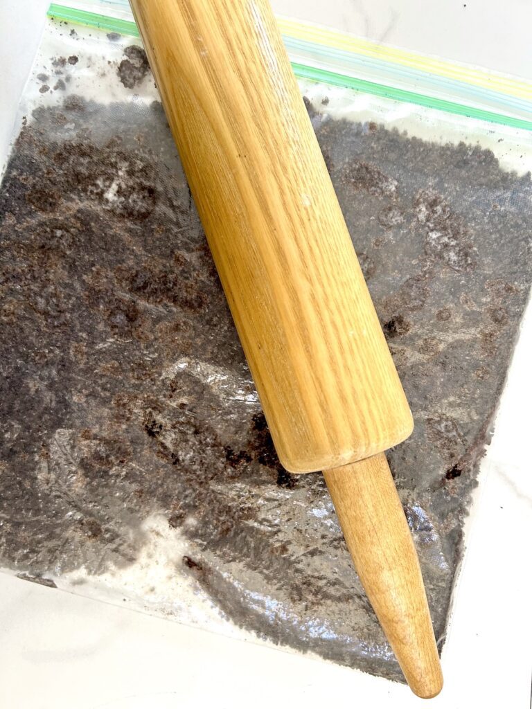 crushed oreos inside a ziplock with a rolling pin on top