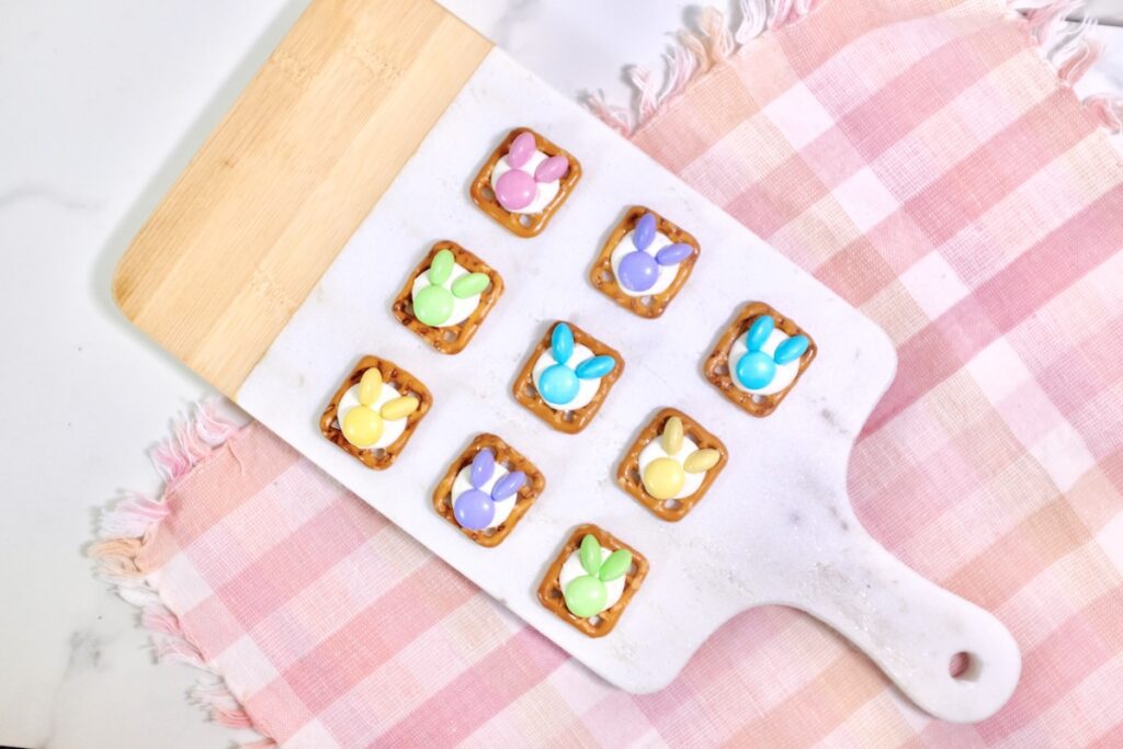 bunny pretzels on wodden chopping board with m&ms candies as toppings