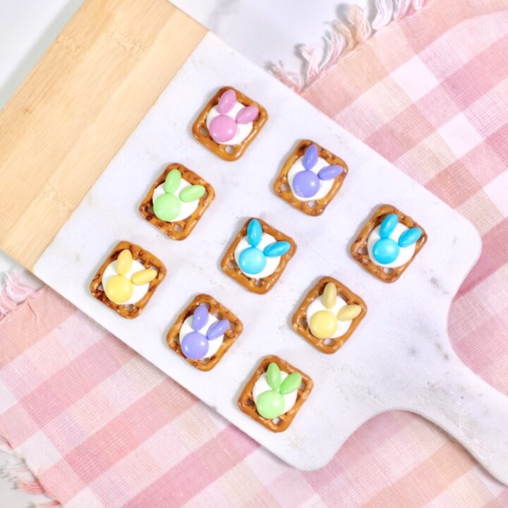 bunny pretzels on wodden chopping board with m&ms candies as toppings