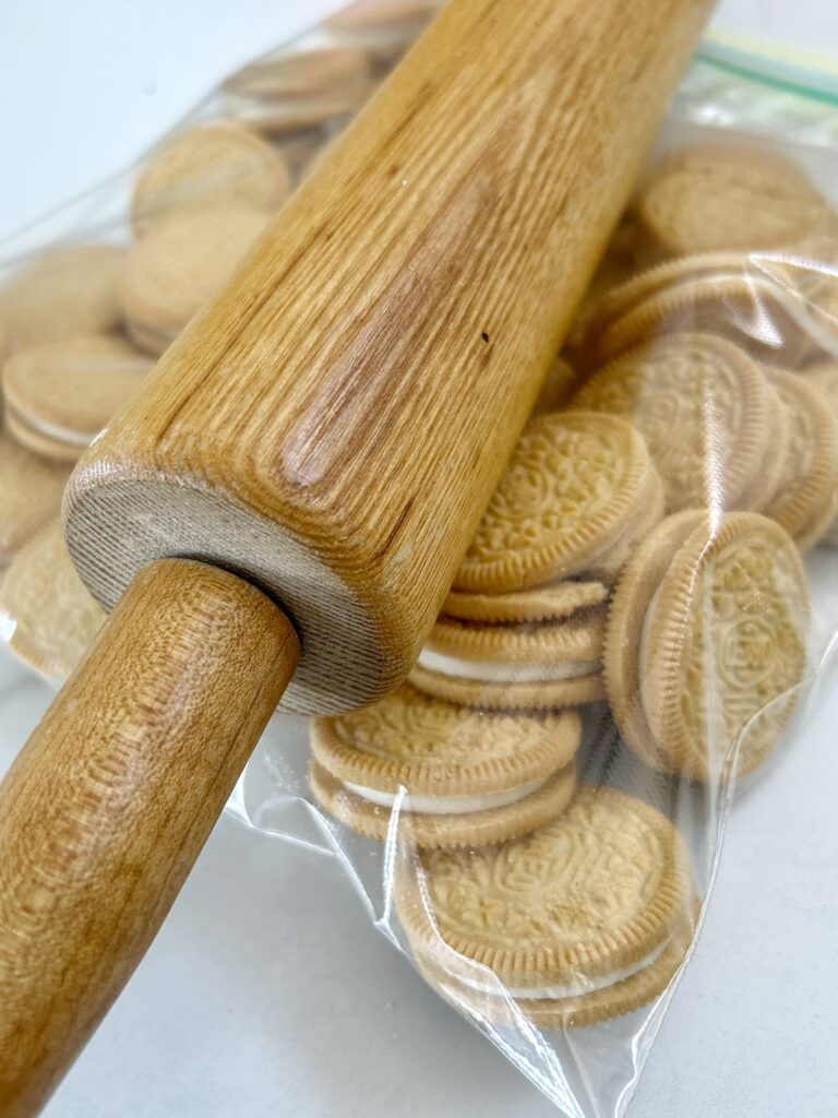 golden oreos inside a ziplock with a rolling pin on top