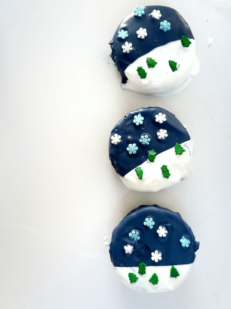 snowglobe dipped oreos with blue and white coating and sprinkles