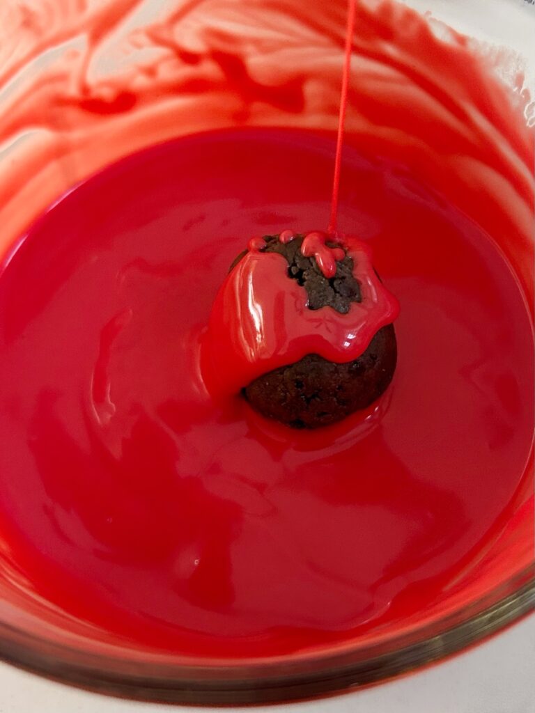 dipping oreo balls into red chocolate melt