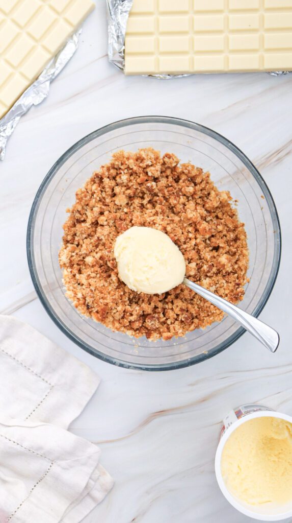 adding frosting to a bowl of crumbled cake