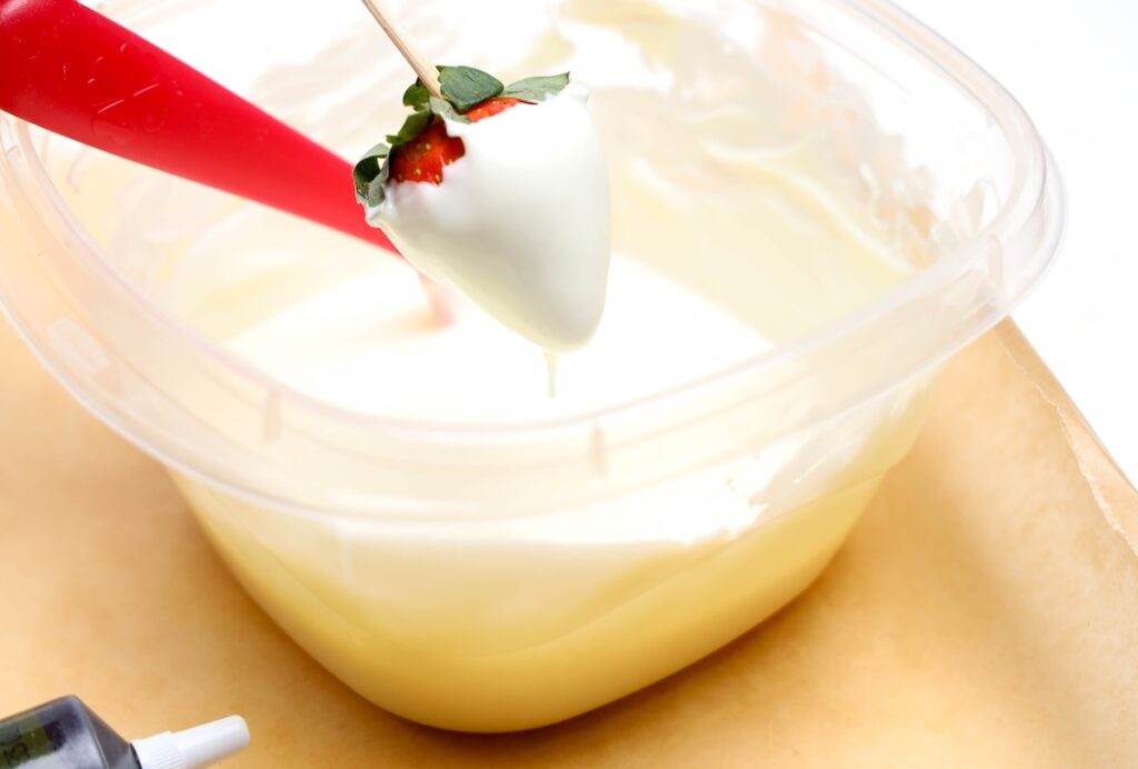 a strawberry being dipped in white chocolate