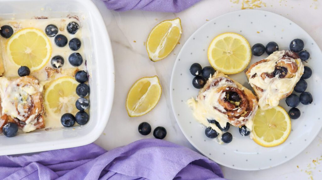 a plate of lemon blueberry cinnamon rolls on a plate and in a white baking dish