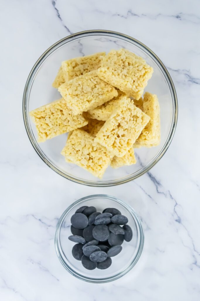 ingredients for ruler rice krispie treats, with rice krispies in a bowl and black candy melts in another