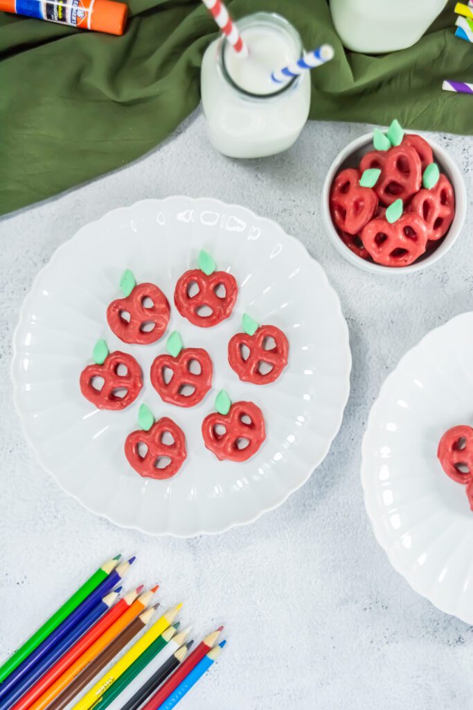 pretzels dipped in chocolate to look like red apples on a plate