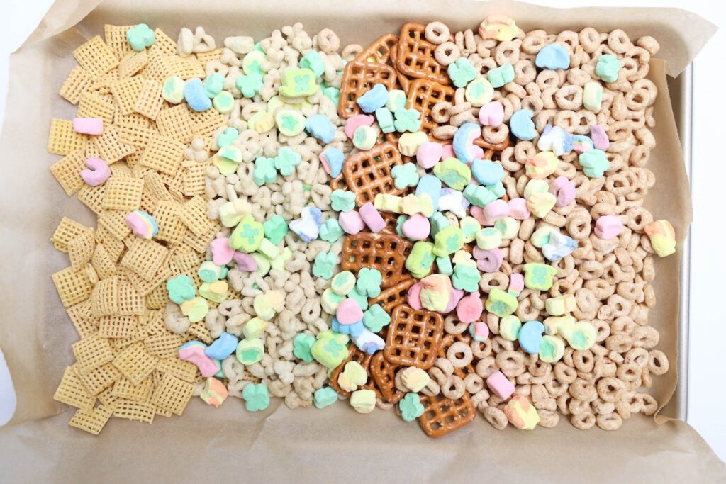 Baking tray now includes colorful Lucky Charms marshmallows scattered over all ingredients, creating a vibrant, festive mix