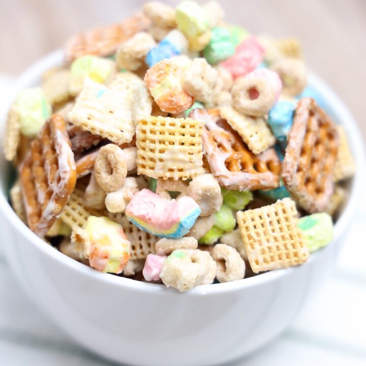 A white bowl filled to the brim with Leprechaun Bait snack mix, highlighting colorful marshmallows, coated cereal, and pretzels