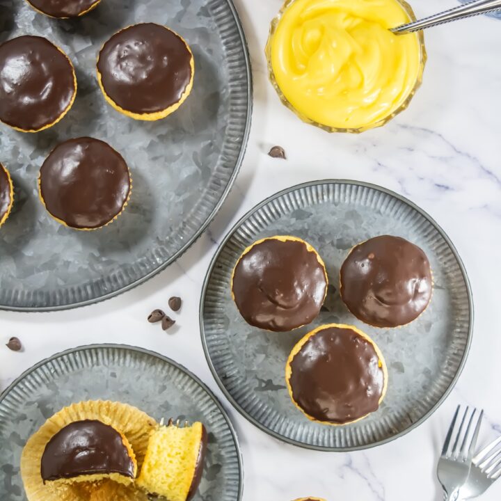 Cross-section view of a Boston Cream Pie cupcake with a bite taken out, showing moist yellow cake and a generous custard center