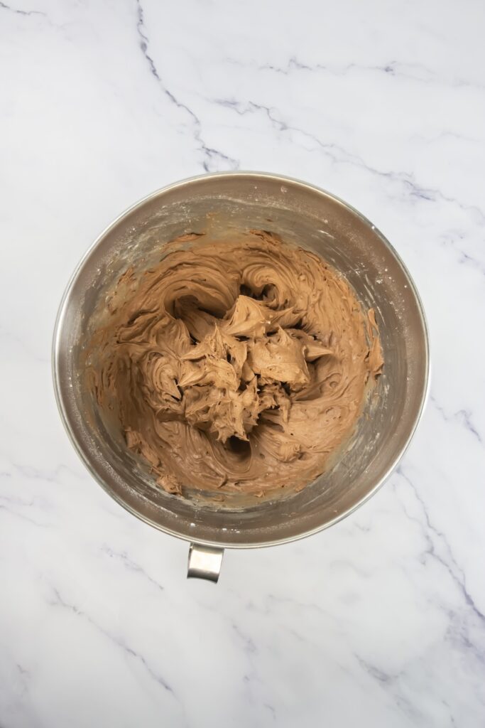 Chocolate cream cheese frosting fully mixed to a smooth, thick consistency in a stainless steel bowl