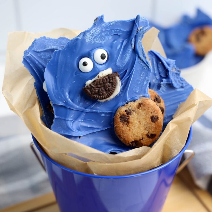 Finished Cookie Monster bark in the same blue bucket, highlighting the playful dessert presentation with edible eyes and cookies