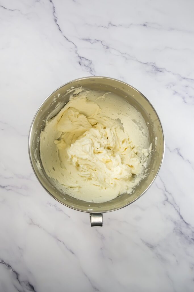 Thick, whipped homemade vanilla frosting in a mixing bowl, with visible swirls and creamy texture.