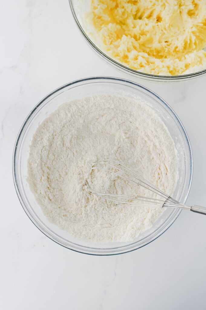 Dry ingredients being whisked in a bowl, including flour and baking soda, before being combined with wet ingredients