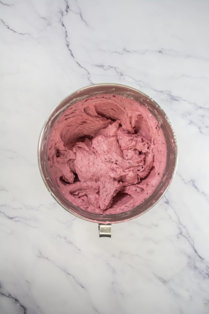 Mixed berry cupcakes topped with swirls of berry frosting, arranged neatly on a wire rack