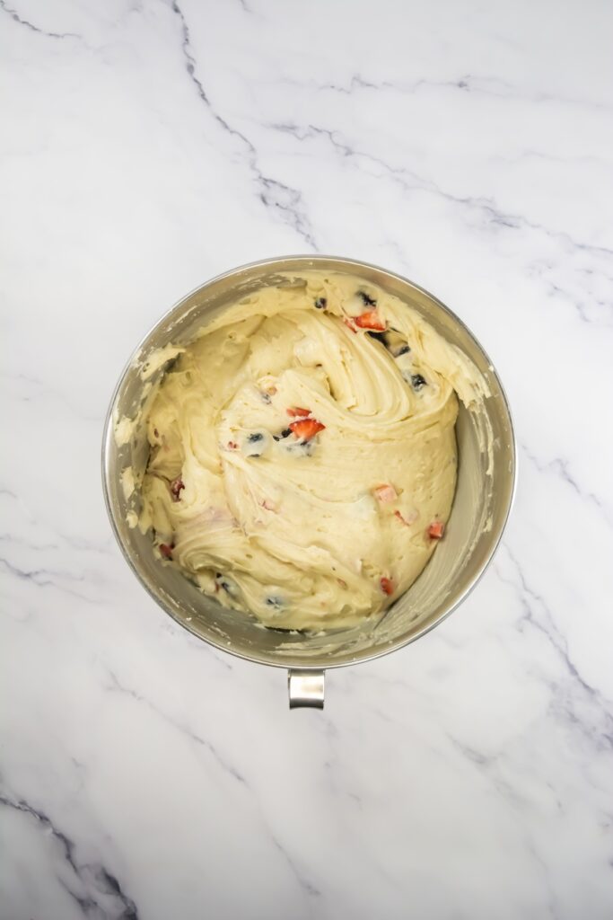 Finished mixed berry cupcake batter with berries stirred in, showing bright specks of fruit throughout
