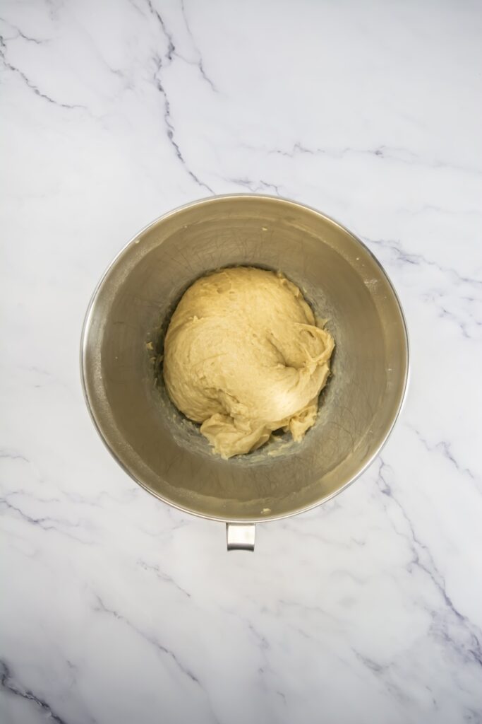 A ball of sweet roll dough resting in a mixing bowl after kneading, smooth and slightly risen