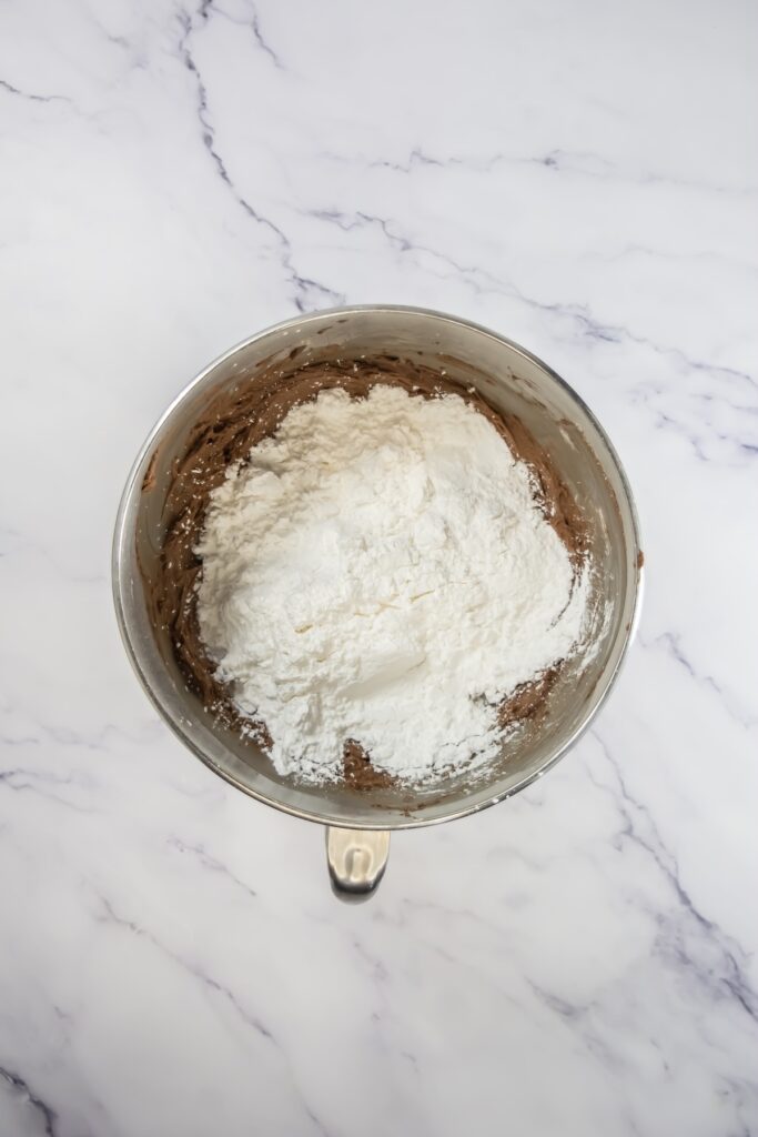Coffee frosting mid-mix, with powdered sugar being blended into the chocolate and butter mixture