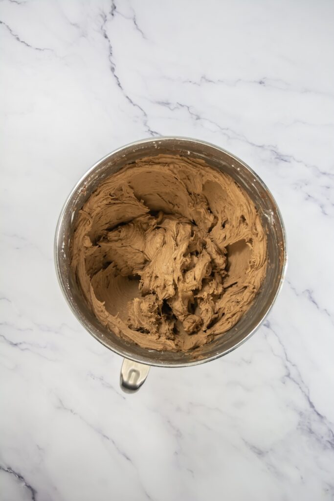 A mixing bowl filled with thick, creamy mocha frosting, whipped to a smooth consistency and ready for piping