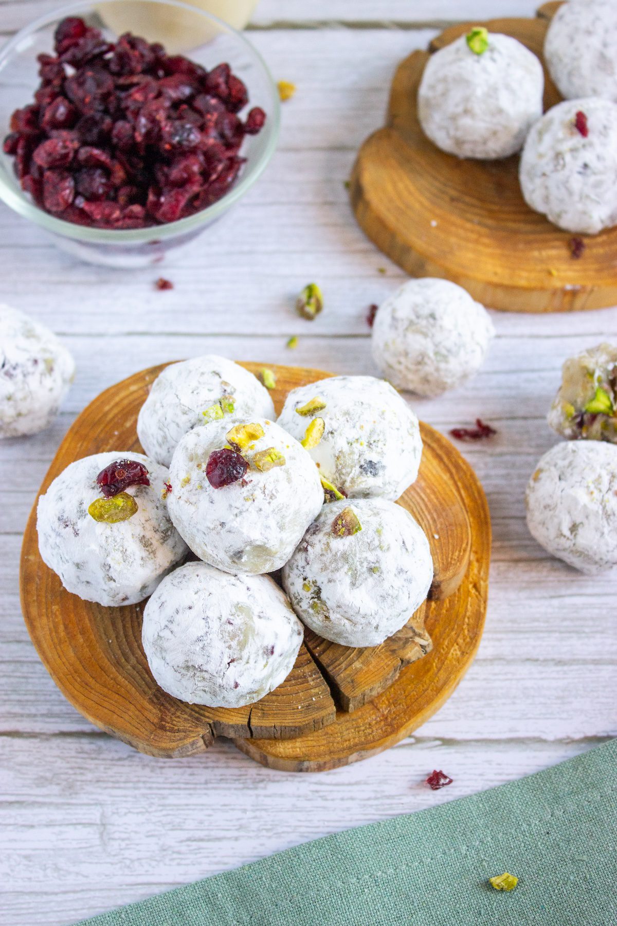 cranberry pistachio eggnog truffles on a wood plate with ingredients in the background