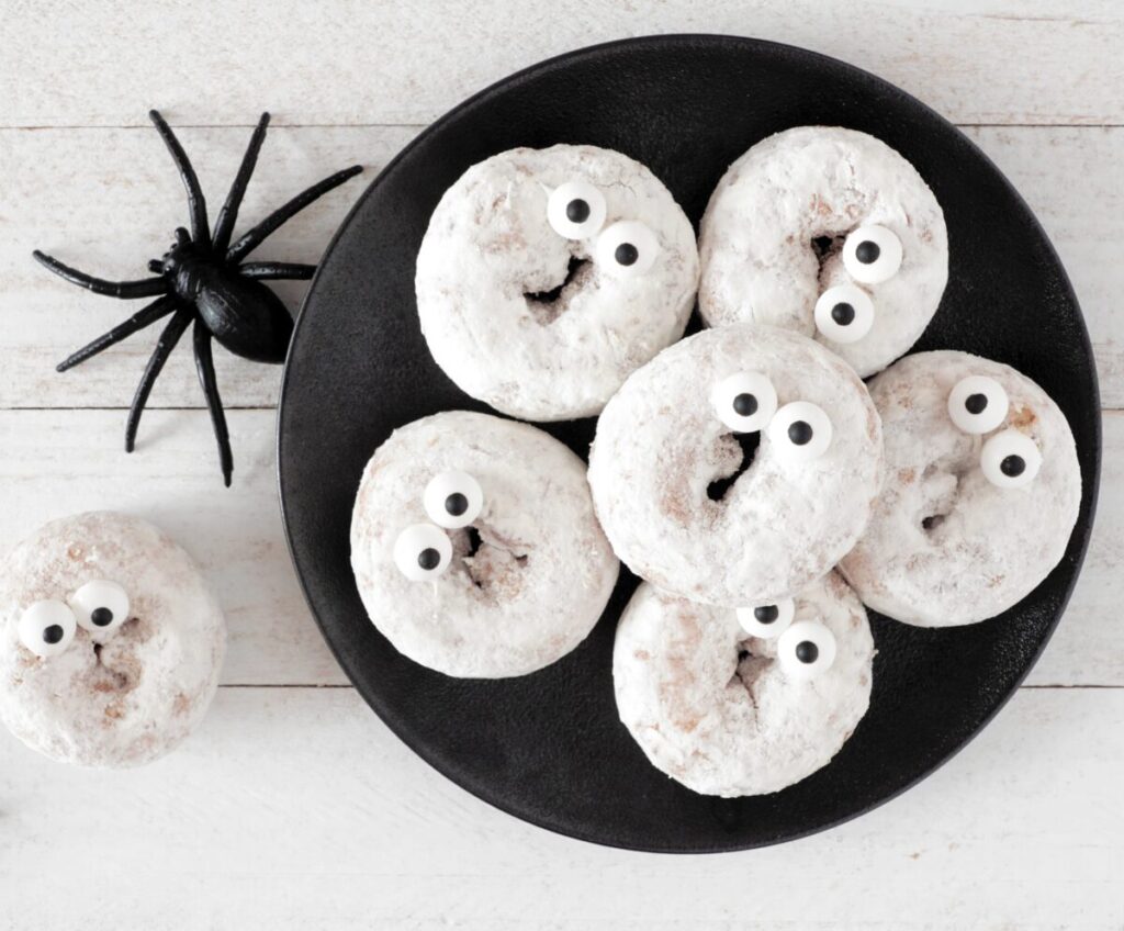 powder donut "ghosts" with candy eyes on a plate