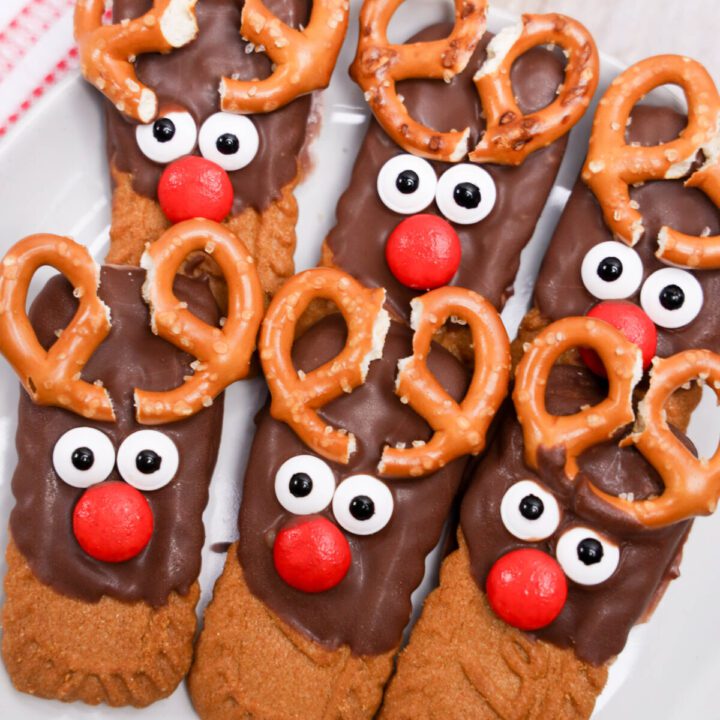 biscoff cookies half dipped in chocolate with pretzel antlers and candy faces to look like reindeer cookies