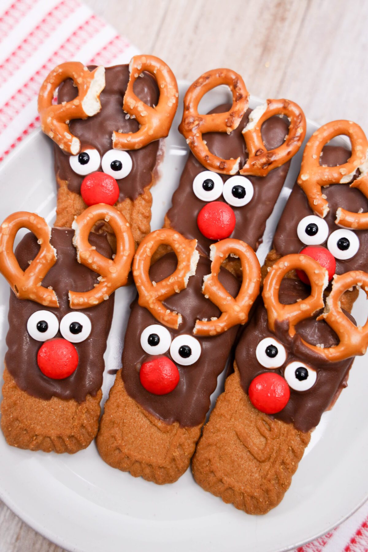 biscoff cookies half dipped in chocolate with pretzel antlers and candy faces to look like reindeer cookies