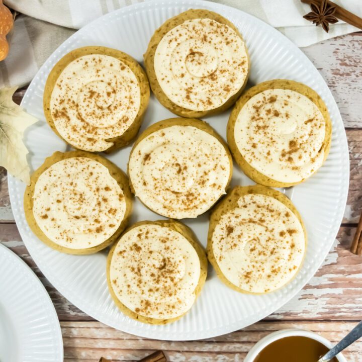 an overhead view of a plate full of caramel pumpkin cookies with frosting