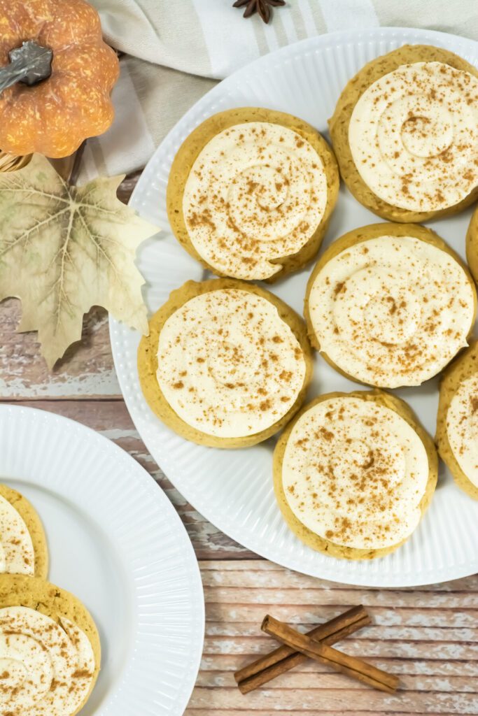 an overhead view of a plate full of caramel pumpkin cookies with frosting