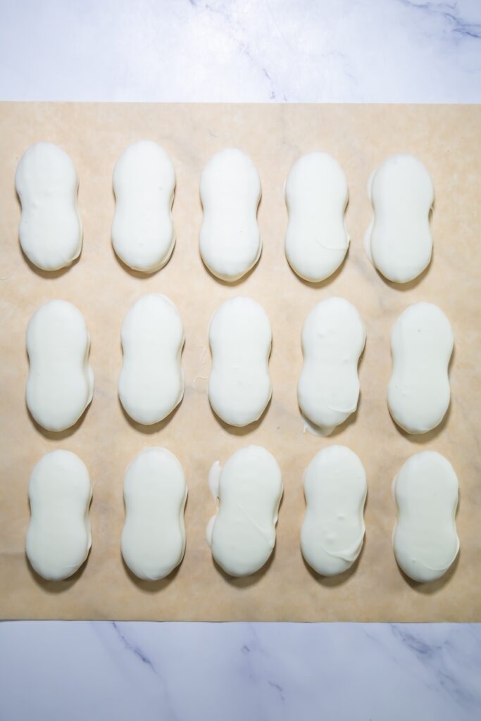 nutter butters dipped in white chocolate on a parchment