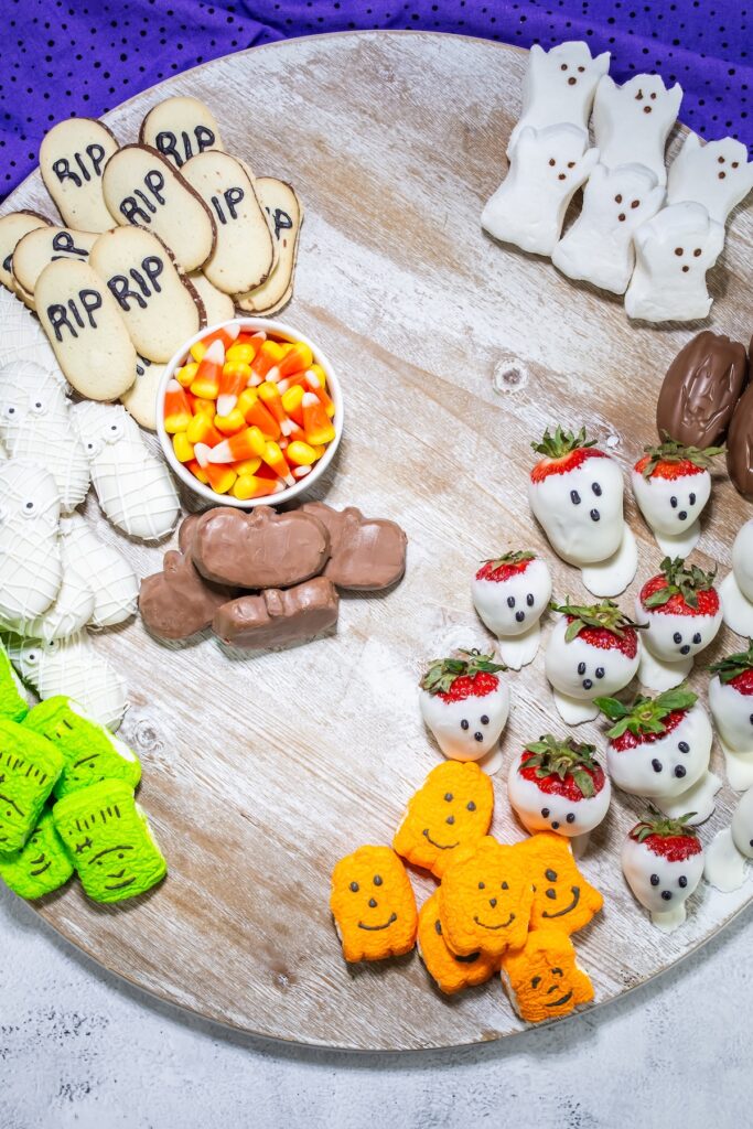 the start of a halloween dessert charcuterie board being assembled with halloween cookies and halloween candy