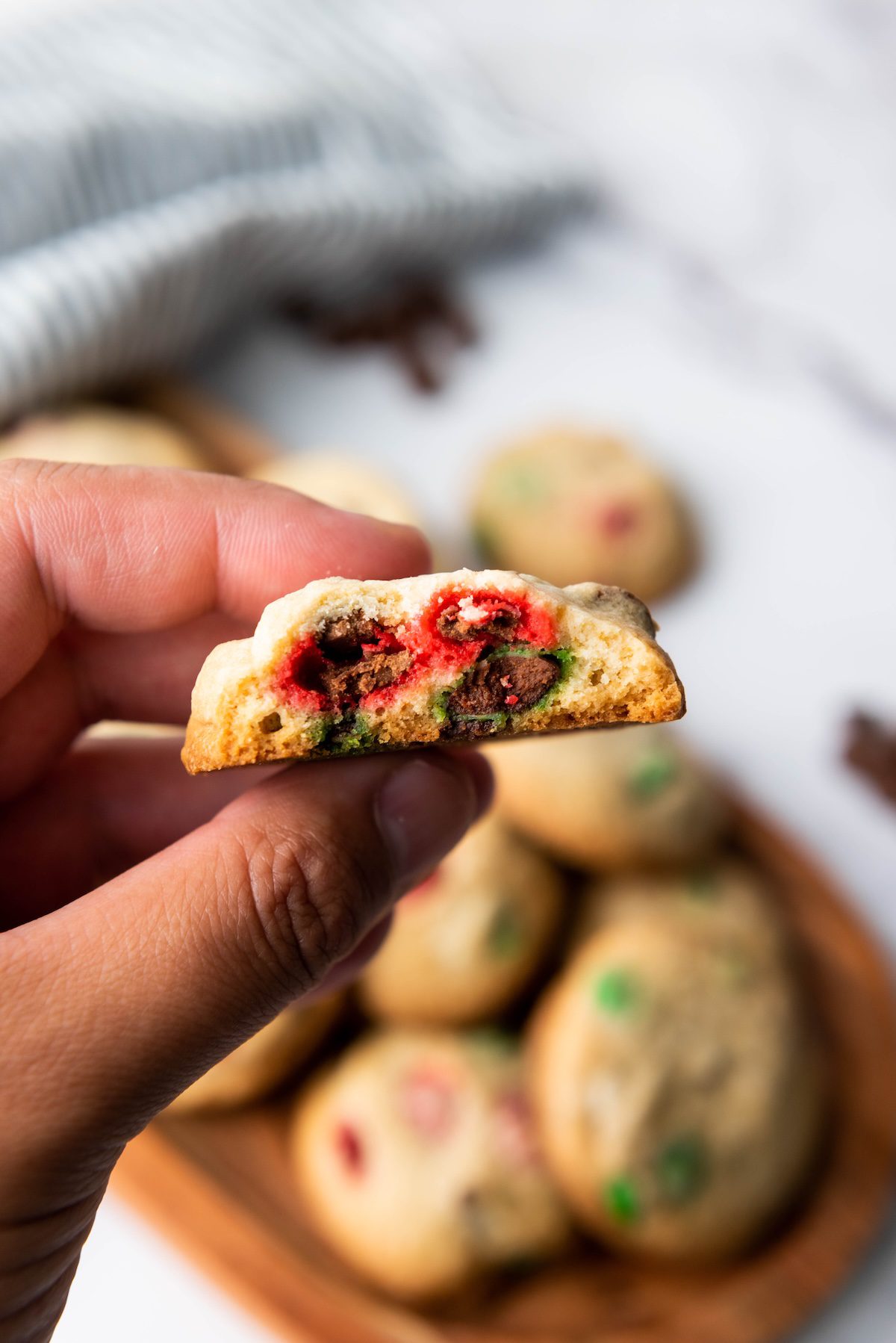 m&m christmas cookie with a bite out held up to the camera to show the middle